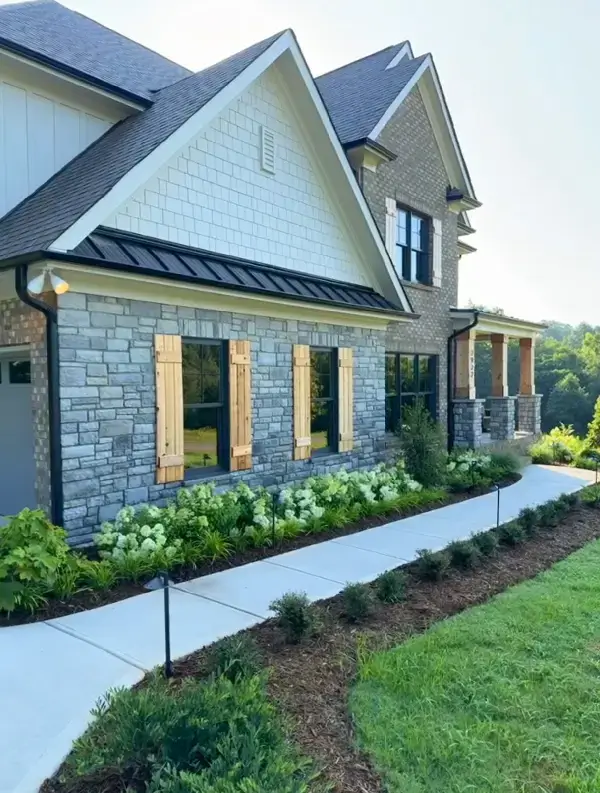 Modern house exterior with stone walls and landscaped garden path.