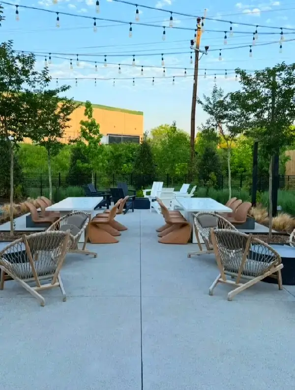 Outdoor patio with wicker chairs and string lights during daytime.