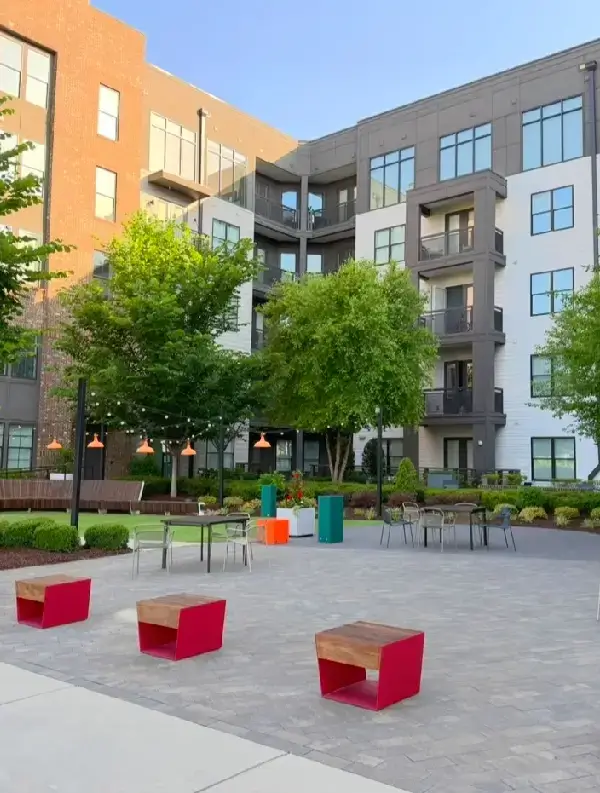 Modern apartment courtyard with seating and greenery.